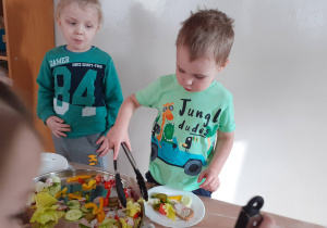 Jakub i Mikołaj przygotowują sobie kanapki przy "szwedzkim stole".