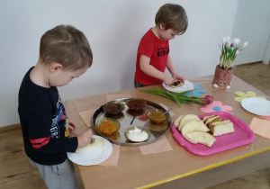 Mikołaj i Adaś przygotowują sobie kanapki stojąc przy "szwedzkim stole".