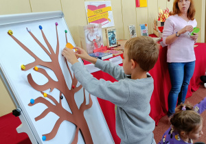 Widok na chłopca, który umieszcza na drzewie liść z „magicznym słowem”.