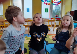 Dzieci dotykają na zmianę językiem do nosa i na brodę.