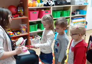 Dzieci z pomoca dużej szczotki czyszczą zęby.