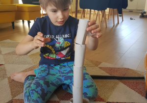 Julek buduje wieżę z rolek po papierze toaletowym.