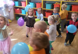 Grupa dzieci bawi się kolorowymi balonami.