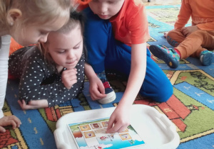 Dzieci dopasowują kwadratowe puzzle do obrazka.