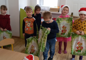 Widok na grupę dzieci, które stoją z prezentami w rękach.