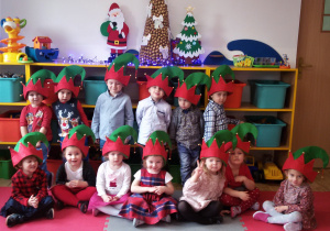 Maluszki pozują do zdjęcia w czapkach elfów na głowach.
