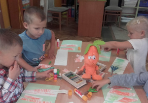 Inna grupa dzieci przykleja elementy marchewki.