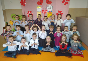 Starszaki pozują do zdjęcia grupowego. Wszystkie dzieci układają dłonie w kształt serca.