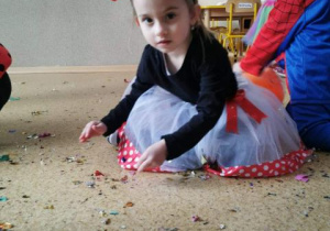 Nadia w przebraniu Myszki Mini zbiera z podłogi konfetti.