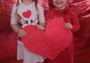 Nela i Laura pozują do zdjęcia trzymając w rękach duże czerwone serce.
