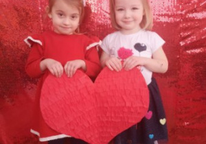 Nadia i Marysia pozują do zdjęcia trzymając w rękach duże czerwone serce.