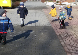 Widok na plac przed budynkiem przedszkola i biegające dzieci.