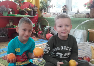 Chłopcy trzymają owoce.