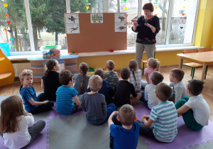 Nauczycielka prezentuje różne zdjęcia dinozaurów.dzieci siedzą przed tablicą
