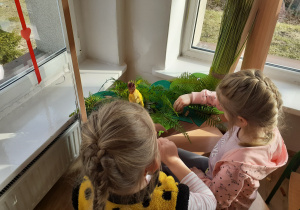 Dzieci odgrywają teatrzyk z dinozaurami