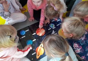Dzieci obserwują plakat i nazywają planety układu słonecznego