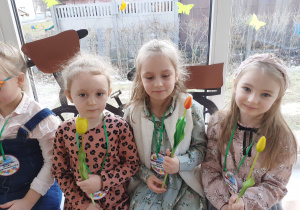 Dziewczynki siedzą na parapecie i trzymają kwiaty