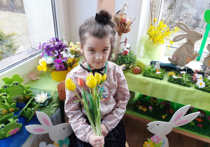 Dziewczynka pozuje do zdjęcia z kwiatami