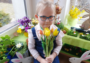 Dziewczynka pozuje do zdjęcia z kwiatami