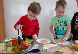 Bartosz i Mikołaj przygotowują sobie kanapki, korzystając ze "szwedzkiego stołu".