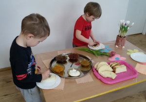 Mikołaj i Adaś przygotowują sobie kanapki stojąc przy "szwedzkim stole".