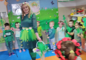 Dzieci stojąc w kole z rekwizytami wiosennymi tańczą przy muzyce „Wiosna w zielonej sukience”. W środku koła stoi „Pani Wiosna” trzymając koszyczek z kwiatkami.