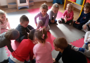 Widok na dzieci siedzące na dywanie.