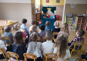 Przedszkolaki oglądają przedstawienie z wykorzystaniem małego teatrzyku lalek.