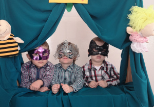 Widok na trzech chłopców w maskach, stojących w oknie teatrzyku.