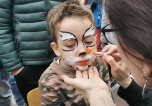 Widok na chłopca korzystającego z atrakcji malowania twarzy- tygrys.