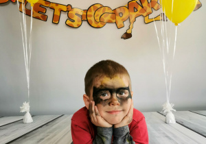 Chłopiec leży na tle fotograficznym i pozuje do zdjęcia wśród balonów.