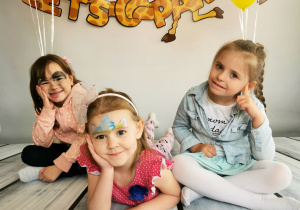Trzy dziewczynki leżą na tle fotograficznym i pozując do zdjęcia.