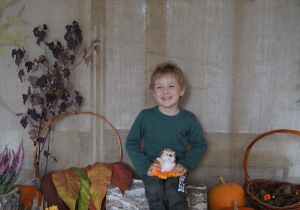 Chłopiec pozuje do zdjęcia z jeżykiem na kolanach na jesiennym tle.