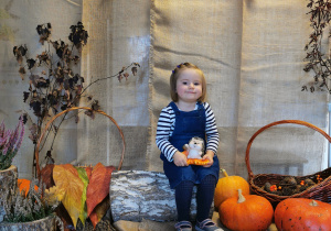 Dziewczynka pozuje do zdjęcia z jeżykiem na kolanach na jesiennym tle.