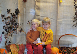 Bracia pozują do zdjęcia z jeżykiem na kolanach na jesiennym tle.