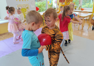 Dzieci tańczą w parach z balonem umieszczonym między brzuszkami.