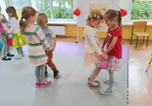 Dzieci tańczą w parach z balonem umieszczonym między kolanami.