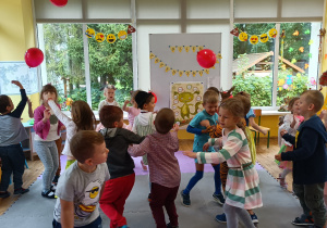 Dzieci podejmują zabawę w odbijanie czerwonego balonika.