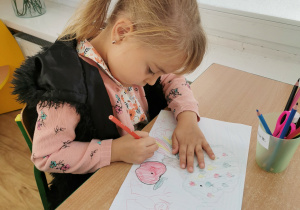 Dziewczynka pozuje do zdjęcia robiąc pracę o jabłku.