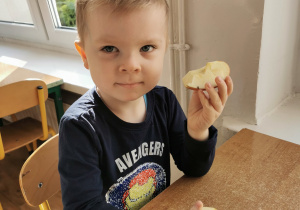 Chłopiec pozuje do zdjęcia w dłoniach trzyma kawałki jabłka, które później zjada.