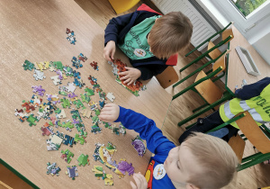 Dwóch chłopców siedzi przy stoliku i układają puzzle.