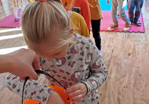 Dzieci częstują się cukierkami wyjmując je z wiaderka w kształcie dyni.