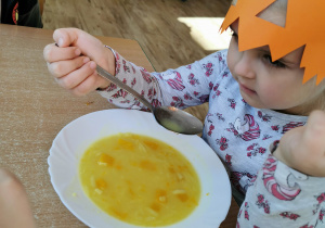 Dziewczynka próbuje zupy dyniowej, która była na obiad.