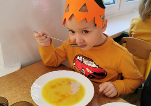 Chłopiec próbuje zupy dyniowej, która była na obiad.
