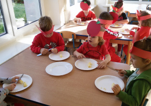 Widok na siedzące przy stolikach dzieci, które kroją obrane ze skóry jabłka.