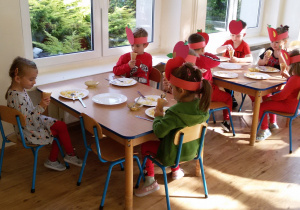 Widok na siedzące przy dwóch stolikach dzieci, które jedzą przygotowane przez siebie desery.