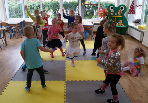 Widok na salę przedszkolną i tańczące dzieci.