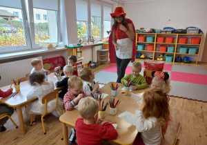 dzieci kolorouja obrazki. Czerwony Kapturek obserwuje ich pracę