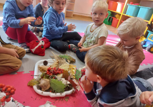 dzieci siedzą w kole w środku jest taca z jesiennymi darami