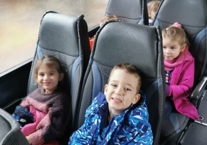 Kilkoro dzieci pozuje do zdjęcia siedząc w autokarze.